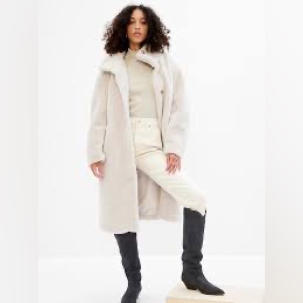 Cozy sherpa coat. Funnel neck. Long sleeves. Button front. Front slant pockets.